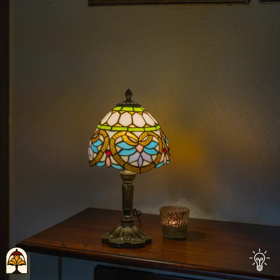 Lampe de table Tiffany Lucette ⌀20 cm allumée dans un intérieur chaleureux – abat-jour en dôme crème avec bandeau décoratif vert, motif de libellule, pied colonne en bronze
