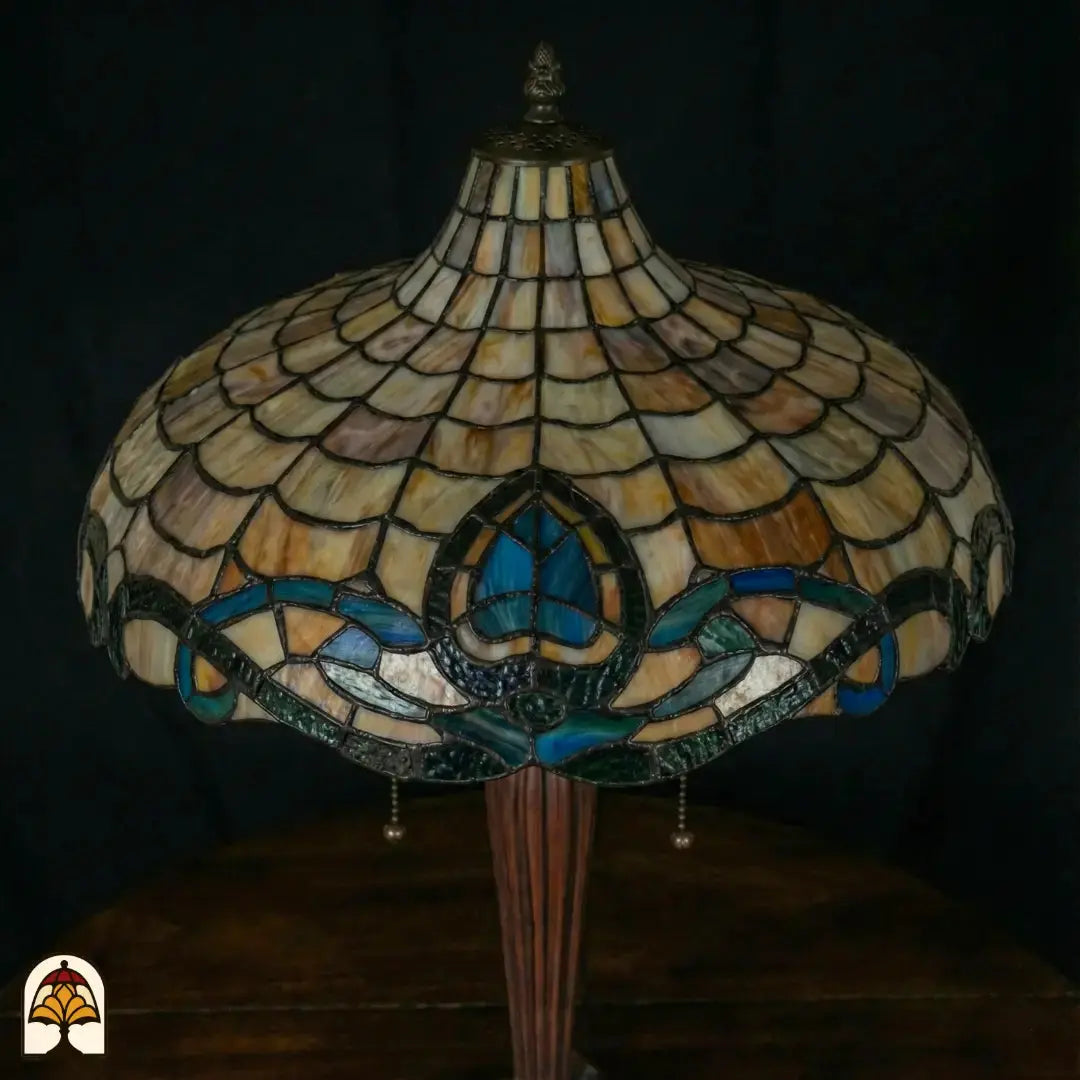 Gros plan abat-jour Tiffany éteint sous un autre angle — motif d'écailles beige/ambré, bordure à motif de lotus turquoise et bleu