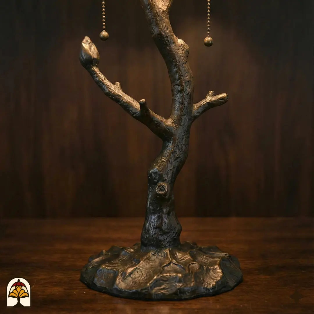 Gros plan pied en forme de tronc d'arbre en bronze lampe de table Tiffany Sylva Verde avec ramifications et interrupteurs à chaînette dorés