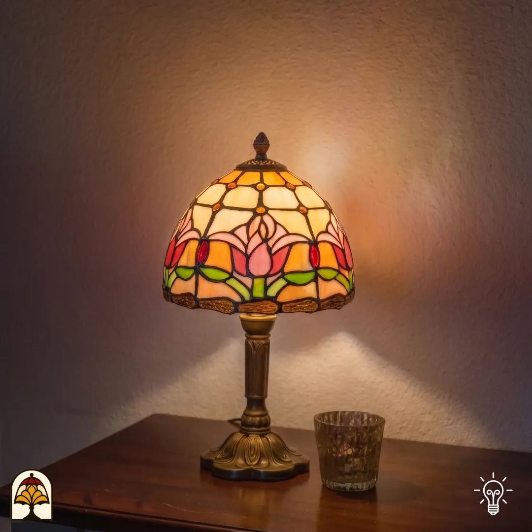 Lampe de table Tiffany Tulipa ⌀20 cm allumée dans un intérieur chaleureux – abat-jour en dôme avec tulipes roses et rouges sur vitrail crème, pied colonne en bronze
