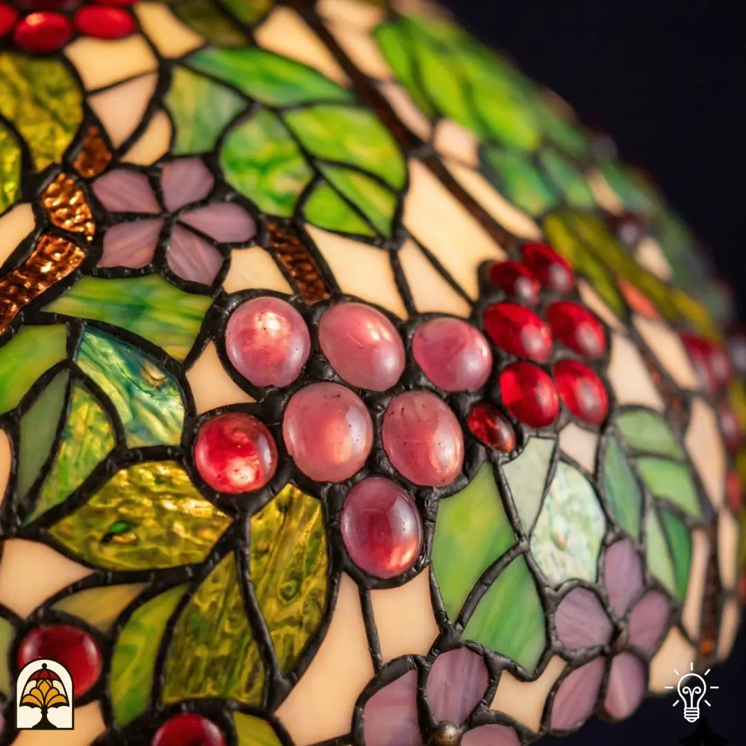 Gros plan abat-jour allumé suspension Tiffany Sylva Berria, grains de raisin roses et rouges en vitrail avec reliefs détaillés, feuilles vertes et vignes brunes