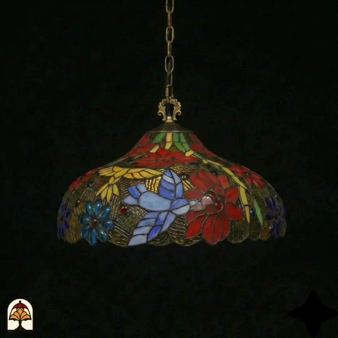 Suspension Tiffany éteinte dans un environnement sombre, forme de dôme avec fleurs de poinsettia rouges, marguerites bleues, papillon blanc-lavande et panneaux de feuilles jaunes, bord inférieur festonné en bronze, suspendue à une chaîne en bronze