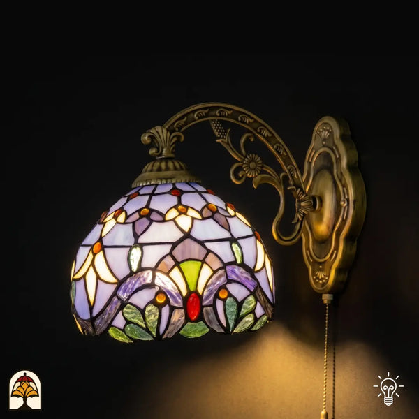 Applique murale Tiffany Royal Mosaic allumée avec abat-jour en vitrail bleu lavande, motifs floraux jaune crème et cabochons en verre colorés sur bras en bronze ouvragé