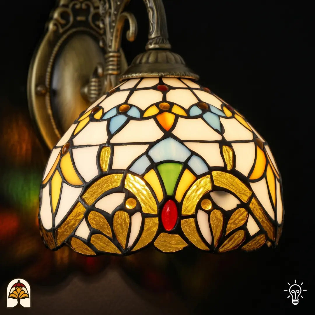 Gros plan de l'abat-jour Tiffany baroque avec formes de feuilles jaune doré, surfaces bleues, accents verts et cabochon ovale rouge en vitrail