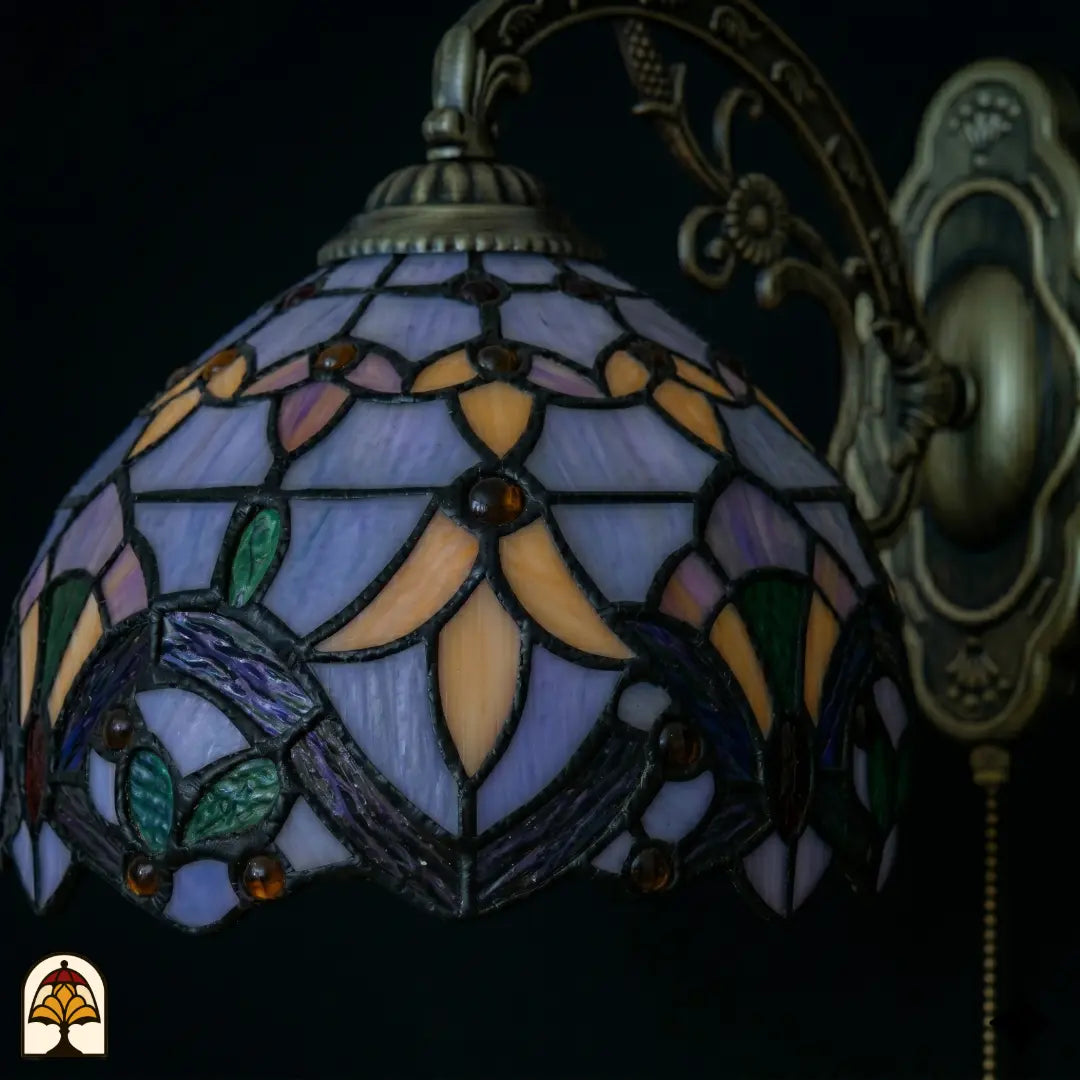Abat-jour éteint de l'applique murale Tiffany Royal Mosaic en gros plan – vitrail bleu lavande, orange et vert avec iris violet et lignes de plomb sombres
