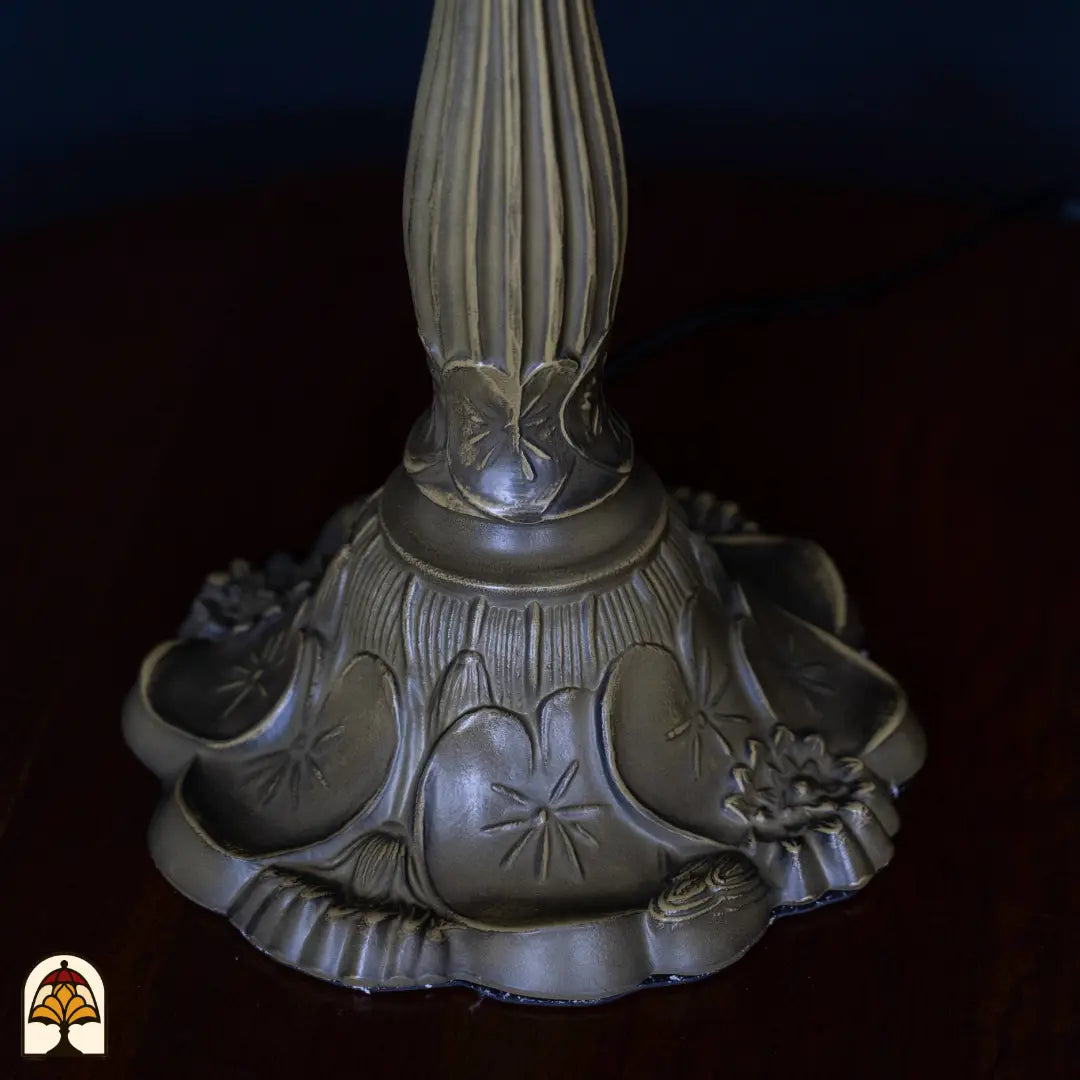 Gros plan pied lampe de table Tiffany Frutta Viva — pied en bronze avec motif décoratif de papillons et de fleurs, fût cannelé