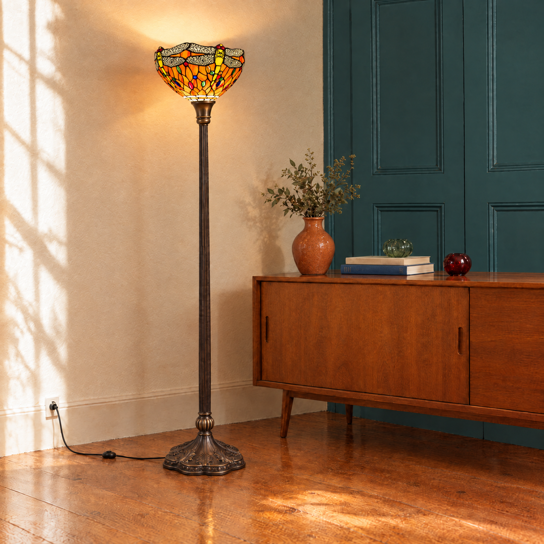 Lampadaire Tiffany Libellula Tramonto en uplighter près d'un buffet en bois et d'une porte verte dans le salon