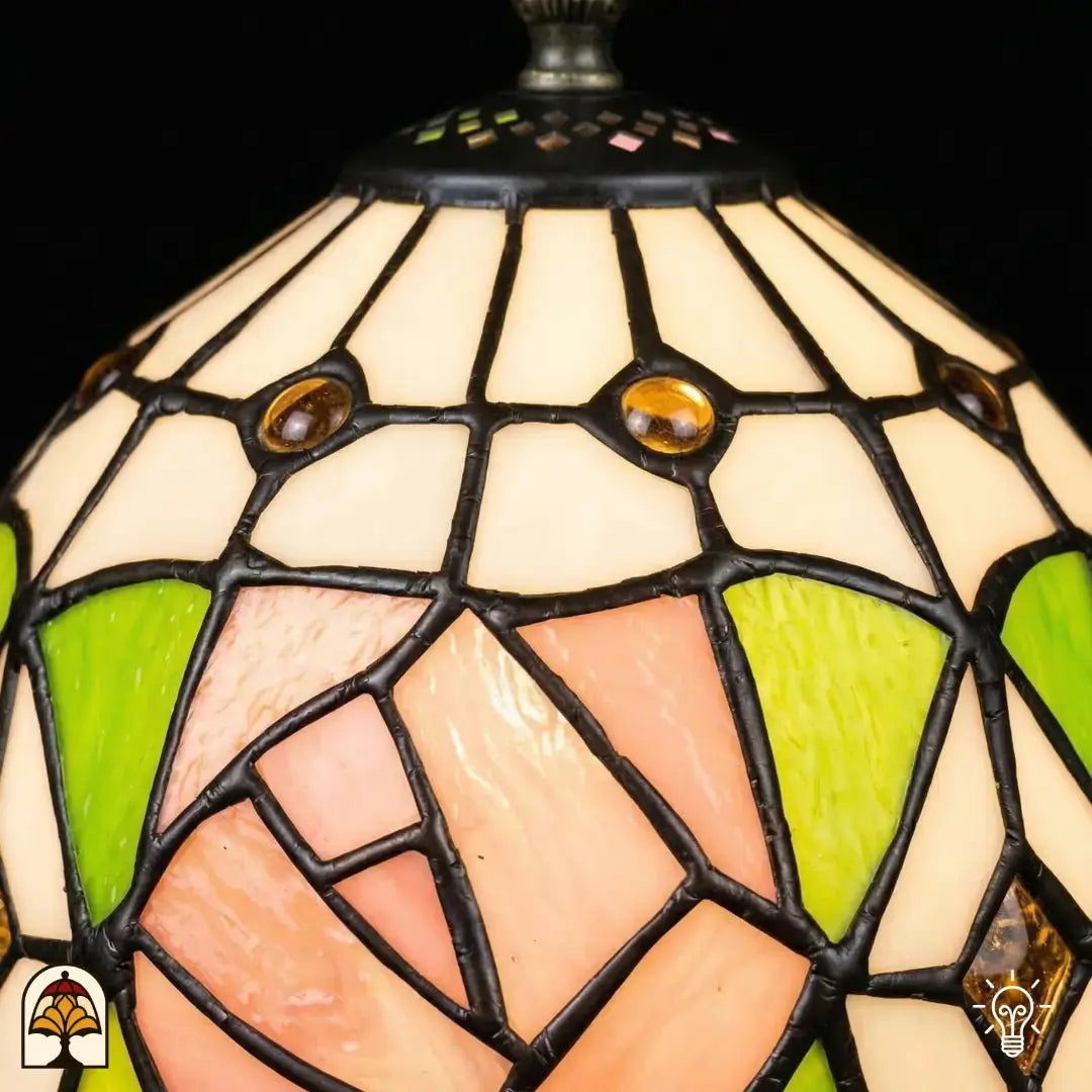Gros plan abat-jour allumé lampe de table Tiffany Rosalia Verde, partie supérieure blanche avec accents ronds dorés, rose rose et feuilles vertes en vitrail