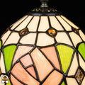 Close-up verlichte kap Tiffany tafellamp Rosalia Verde, witte bovenkap met gouden ronde accenten, roze roos en groene bladeren in glas-in-lood