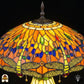 Detailopname van tiffany lamp kapbovenzone verlicht, amberkleurig glas met blauwe en groene ovale glaskralen in een band en rode ronde kralen, bronzen ventilatieplaat en puntfinial bovenaan