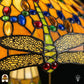 Detailopname van tiffany lamp libelle-rand onderaan de kap verlicht, geel-goudkleurige libellen met geaderde vleugels in glas-in-lood, blauwe en bruine ovale glaskralen en rode ronde kralen