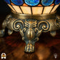 Detailopname van tiffany lamp bronzen siervoet met leeuwenpoten en acanthusblad-ornament, crème en oranje glas-in-lood en blauwe glaskralen bovenaan zichtbaar