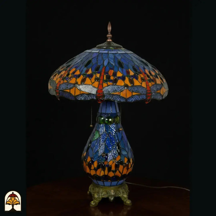 Tiffany lamp tafellamp onverlicht, koepelvormige kap met blauw glas en libellemotieven langs de rand, oranje en rode glaskralen, peervormige blauwe glas-in-lood voet en bronzen leeuwenpootvoet