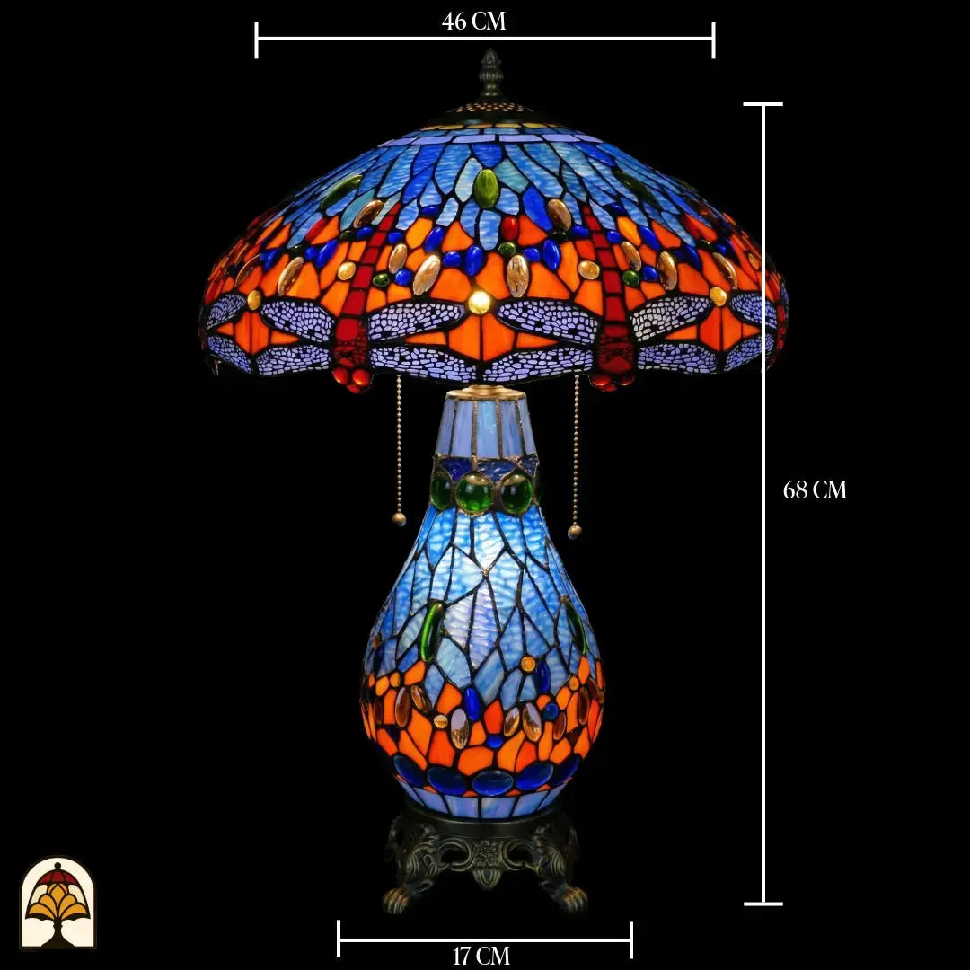 Lampe de table Tiffany avec indications de dimensions : diamètre de l'abat-jour 46 cm, hauteur totale 68 cm, diamètre du pied 17 cm ; abat-jour allumé avec verre bleu, motifs de libellule et cabochons en verre bleus visibles