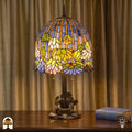 Verlichte Tiffany tafellamp Pond Lilia op houten tafel voor gordijnen, blauwe en gele strepen met witte waterlelies en gekleurde accenten, boek ernaast