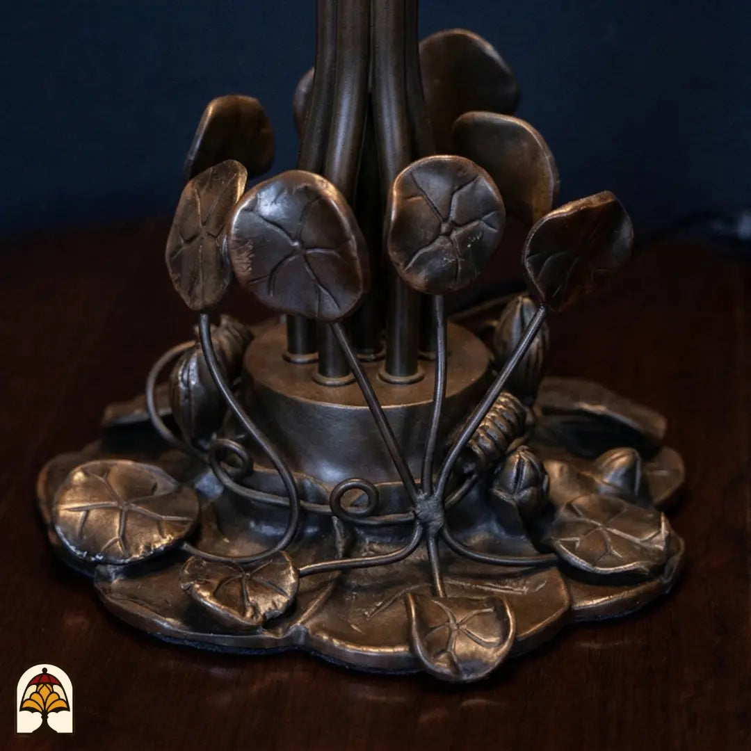 Gros plan pied en bronze lampe de table Tiffany Pond Lilia – motif de feuilles de nénuphar et rinceaux ouvragés