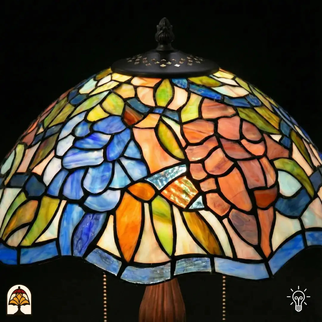 Gros plan abat-jour en dôme allumé lampe de table Tiffany Florentia Blu, fleurs bleues et motifs de feuilles orange-rose et vertes en vitrail