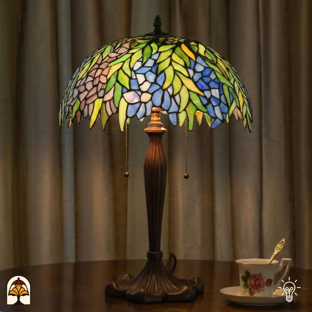 Lifestyle — lampe de table Tiffany allumée sur une table devant des rideaux beiges, tasse de thé avec soucoupe à côté