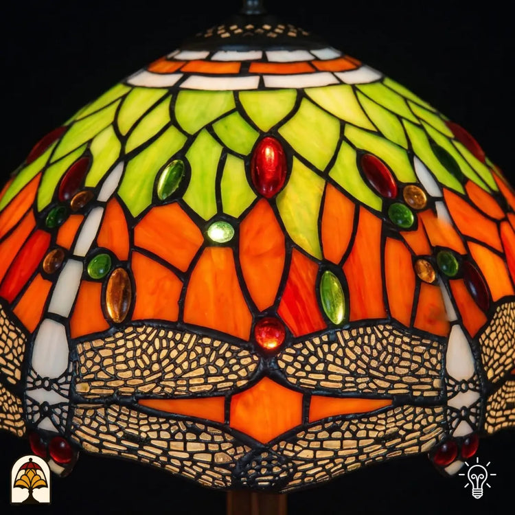 Close-up verlichte kap Libellula Azul ⌀30, oranje glas-in-lood panelen met geel-groene bladmotieven, rode en groene ovale juwelen en libellenfries onderaan
