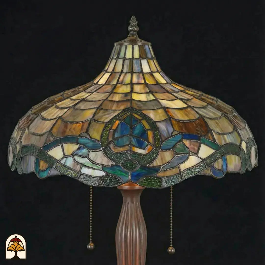 Gros plan abat-jour Tiffany éteint — motif d'écailles ambré/beige, motif de lotus turquoise, bordure Art nouveau bleue et verte, interrupteurs à chaînette