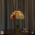 Tiffany tafellamp Colibrì verlicht op donkere bijzettafel voor grijze gordijnen — theekopje met schoteltje rechts naast de lamp