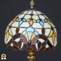 Close-up onverlichte koepelkap Tiffany tafellamp Baroque – crème en turquoise glas met bruine barokke bladvormen en rode edelsteen