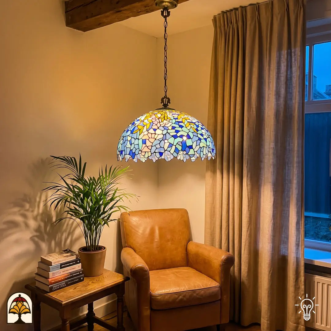 Suspension Tiffany Drizzle Bleu ⌀50 cm allumée dans un intérieur chaleureux – motifs floraux en vitrail bleu et turquoise, accents de feuilles jaunes, chaîne en bronze
