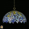 Onverlichte Tiffany hanglamp Drizzle Bleu ⌀50 op donkere achtergrond, lila-blauwe en turquoise koepelkap met gele bladaccenten en geschulpte rand, bronzen ketting