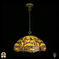 Onverlichte Tiffany hanglamp Libellula Aurelia ⌀50 op donkere achtergrond, grote koepelvormige kap met gele glas-in-lood panelen, libellenfries onderaan, rode en blauwe juwelen, bronzen ketting en plafondrozet