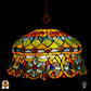 Tiffany lamp hanglamp verlicht van dichterbij, koepelvormige kap met ambergele bovenzone met groene glaskralen en roodbruine ovale kralen, onderzone met gele arabesken, lichtblauwe bloemvormige kralen en rode ronde kralen op transparant glas
