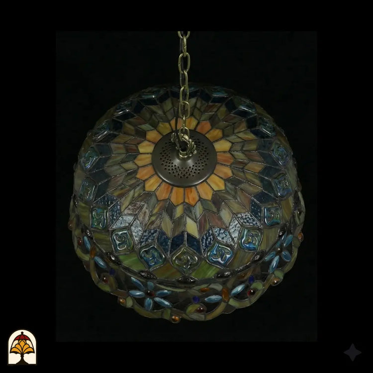 Onderkant bovenaanzicht van tiffany lamp hanglamp onverlicht, koepel met stralend patroon van amberkleurig glas en blauwe vlakken, groene glaskralen, bronzen ventilatieplaat zichtbaar in het midden