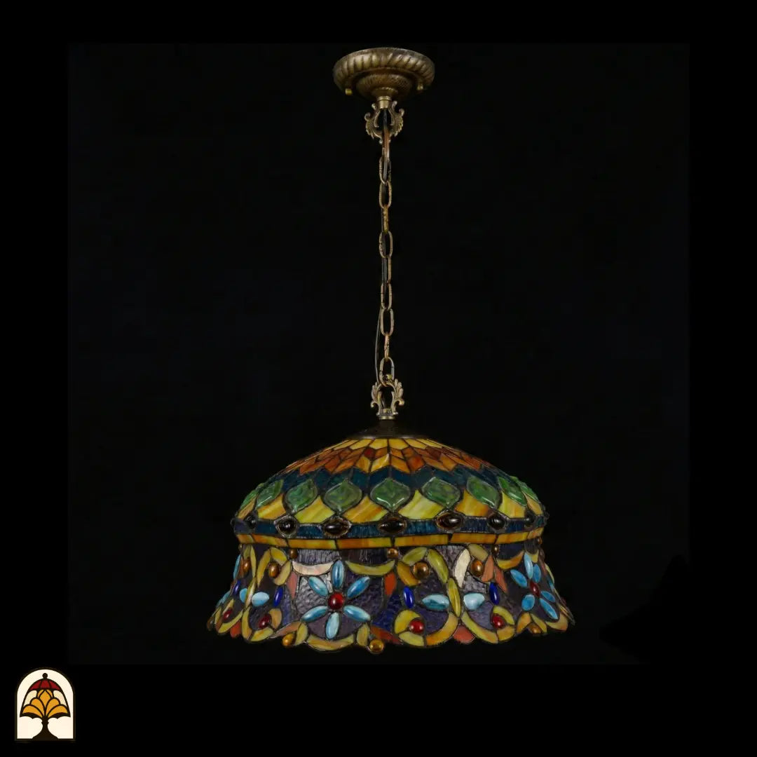 Suspension Tiffany éteinte, vue complète avec rosace de plafond en bronze et chaîne en bronze, abat-jour en dôme avec zone supérieure à cabochons en verre verts et zone inférieure à cabochons en forme de fleur bleu clair, bord festonné