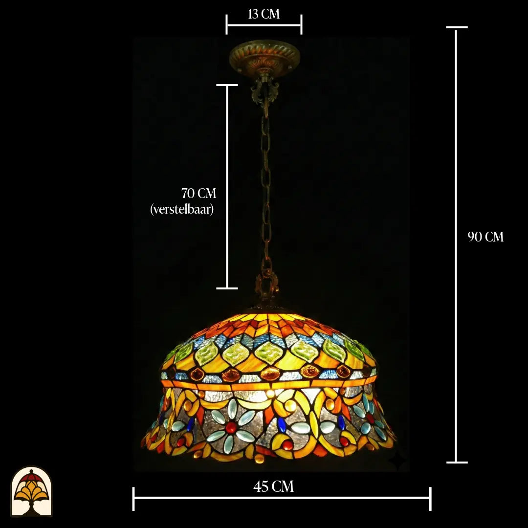Suspension Tiffany avec indications de dimensions : diamètre de l'abat-jour 45 cm, hauteur totale 90 cm, chaîne 70 cm réglable, rosace de plafond 13 cm ; abat-jour allumé avec cabochons en verre verts en losange et cabochons en forme de fleur bleu clair visibles