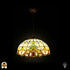 Verlichte Tiffany hanglamp Barok ⌀40 op donkere achtergrond, koepelvormige kap met crème glas-in-lood panelen, gele tulpmotieven, blauw-groene waaier, gouden barok rolwerkrand onderaan, rode juweel centraal, bronzen ketting en plafondrozet