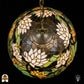 Bovenaanzicht van tiffany lamp hanglamp verlicht, koepel met witte en geel-oranje lotusbloemen en groene waterleliebladen rondom de centrale bronzen ventilatieplaat, donkerblauw glas in het midden