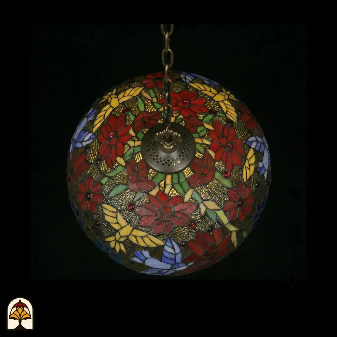 Vue de dessous d'une suspension lampe Tiffany éteinte, dôme au motif symétrique de fleurs de poinsettia rouges, panneaux de feuilles jaunes, feuilles vertes, papillons lavande et accents floraux bleus, plaque d'aération centrale en bronze visible
