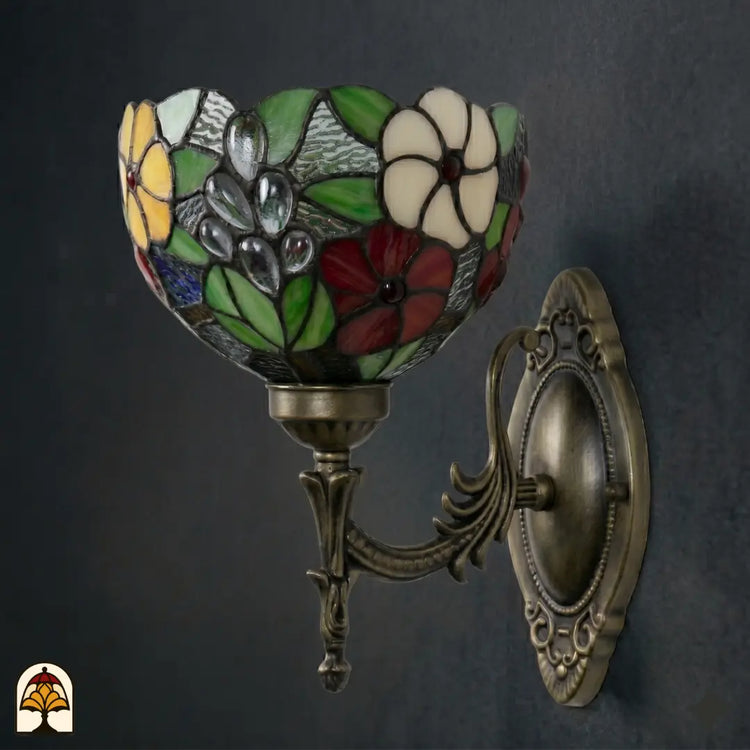 Onverlichte Tiffany wandlamp Floral Garden van opzij, kap met groene bladeren, rode, witte en gele bloemen en grijze druppels in glas-in-lood