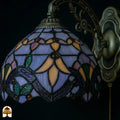 Onverlichte kap Tiffany wandlamp Royal Mosaic close-up – lavendelblauw, oranje en groen glas-in-lood met paarse iris en donkere loodlijnen