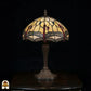 Onverlichte Tiffany tafellamp Libelle Elegance op donkere achtergrond, geel-amber kap met libellenmotieven langs de rand, bronzen geribbelde vaasvoet