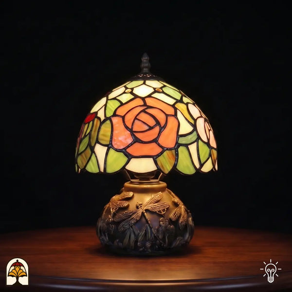Lampe de table Tiffany Silvae Rosea ⌀20 cm allumée – abat-jour sphérique avec rose orange et feuilles vertes sur pied à libellules
