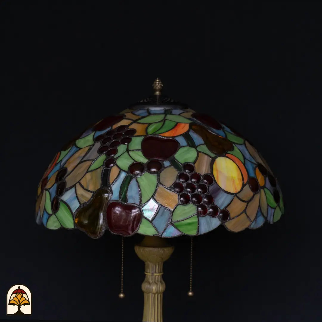 Gros plan abat-jour lampe de table Tiffany Frutta Viva éteinte — raisins violets, pommes rouge foncé, poire verte, feuilles vertes, surfaces bleues
