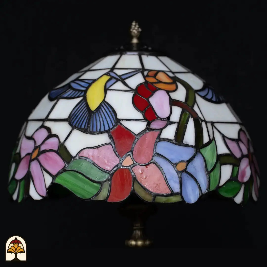 Gros plan abat-jour lampe de table Tiffany Colibrì éteinte — verre blanc avec colibri (jaune/bleu), fleurs rouges, orange, roses et bleues, feuilles vertes