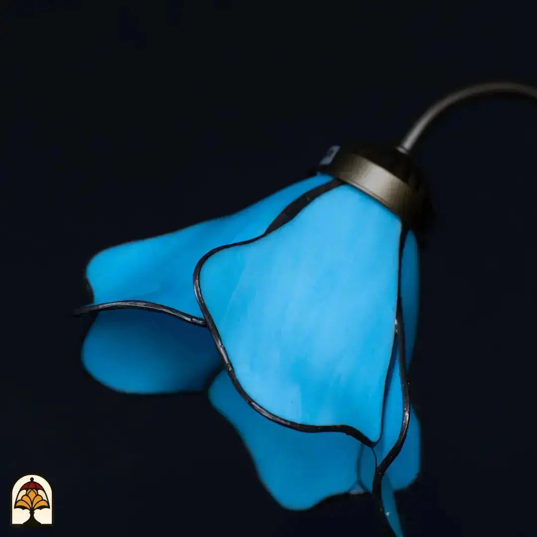 Gros plan abat-jour fleur de lotus bleue éteint — pétales en verre bleu déployés en éventail, fond sombre