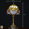 Maatafbeelding Tiffany tafellamp Lucette: 20 cm breed, 38 cm hoog, voet 10 cm – kap met gouden libelle-ornamentiek en groene sierband op bronzen kolomvoet