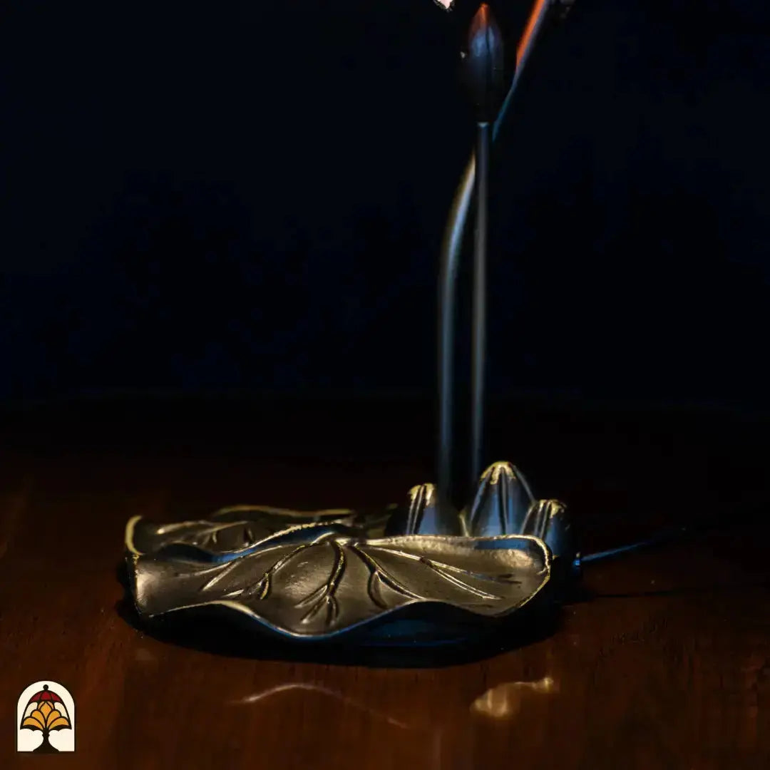 Gros plan pied — base en bronze doré en feuille de lotus avec tige courbée, câble d'alimentation visible