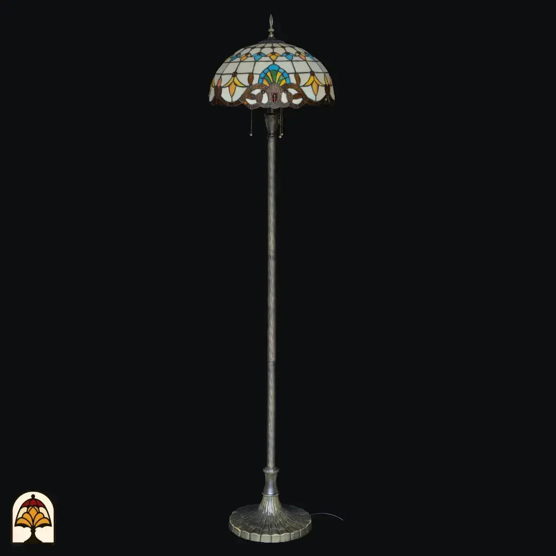 Gros plan abat-jour allumé lampadaire Tiffany Barok vu de face — verre crème/ambré avec motif central bleu/vert, éléments en forme de feuilles jaunes et orange, bordure inférieure baroque en bronze