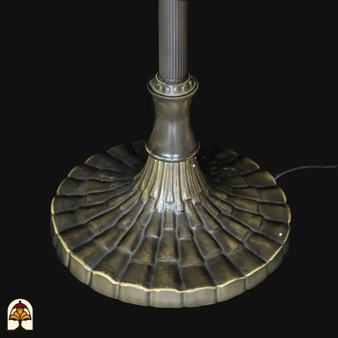 Gros plan pied lampadaire Tiffany Libellula Aurea — large base ronde en bronze oxydé avec motif décoratif de nervures, câble d'alimentation visible