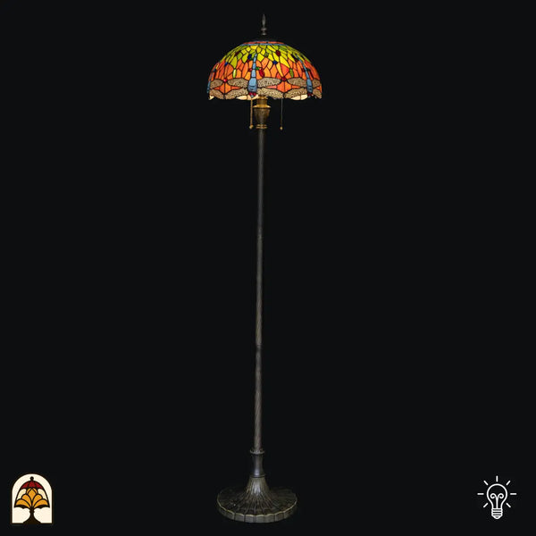 Lampadaire Tiffany Libellula Azul allumé sur fond noir – abat-jour en dôme bleu avec bordure de libellules, long fût, large pied en bronze