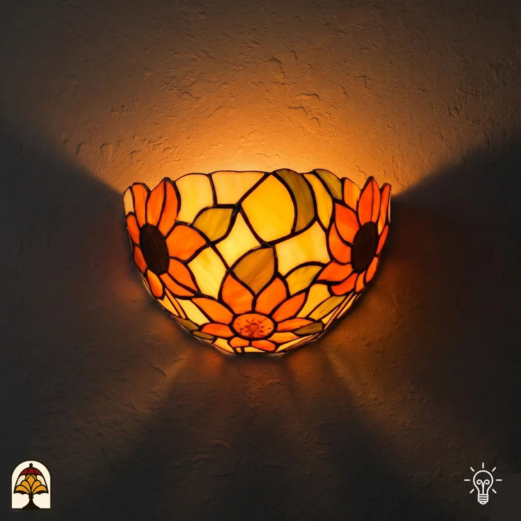 Tiffany wandlamp Solea Girasole verlicht op muur – halfronde kap met zonnebloemen in oranje en geel glas